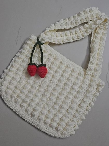 My Strawberry Popcorn tote bag, featuring a fun, bubbly texture from the popcorn stitch. I added a little cherry charm for a playful touch on this creamy white tote.
