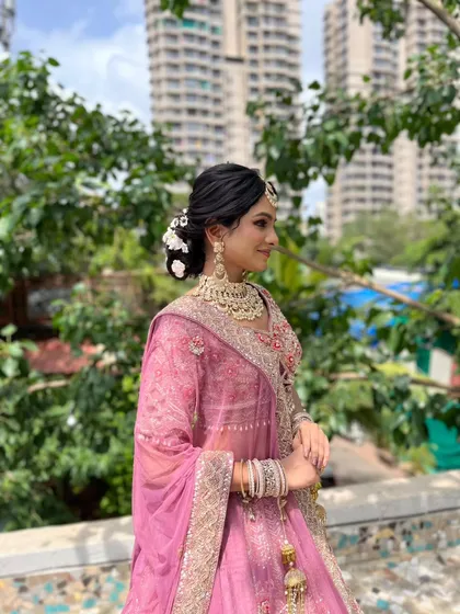 This bride's sangeet makeup was designed for a daytime celebration. The subtle elegance of the look enhances her features without being overpowering, perfectly matching her pink lehenga and the outdoor setting.
