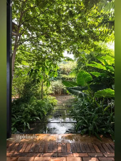 A water channel runs through a brick patio, surrounded by lush greenery. The sound and sight of moving water adds a dynamic and soothing element to this intimate garden space.
