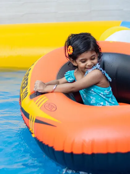 This smiling girl is having a great time in her inflatable boat. These individual boats give kids a sense of independence as they navigate the pool.