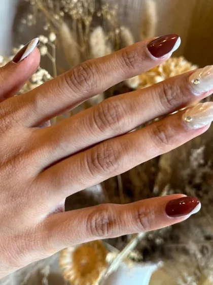 A sophisticated and edgy look combining a deep, wine-red with a pearly, shell-like white accent nail.