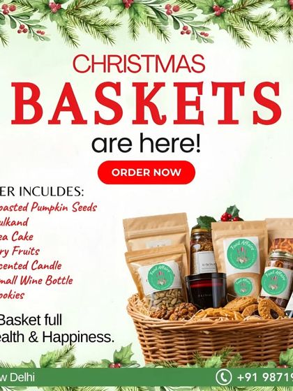 Our Christmas Baskets are here. This graphic shows a festive basket filled with Roasted Pumpkin Seeds, Gulkand, Tea Cake, Dry Fruits, Cookies, and a small bottle of wine.