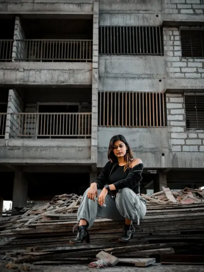 A commanding pose with the model seated, looking directly at the camera, exuding confidence in the middle of the industrial setting.