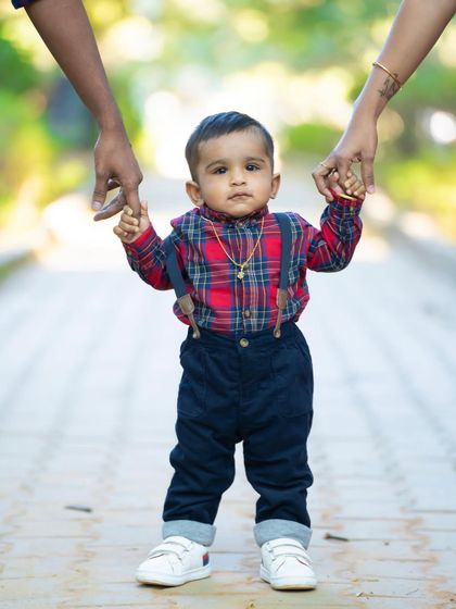 A little boy standing tall, holding his parents' hands. This shot perfectly captures the feeling of support and love on his first birthday.