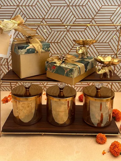 A two-tiered stand makes for a stunning presentation. This hamper includes crystal-topped jars, beautifully wrapped gift boxes, and elegant elephant-shaped T-light holders, creating a memorable and useful Diwali gift.