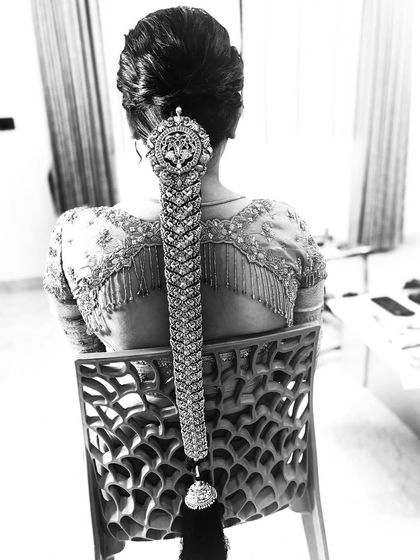 A black and white shot highlighting the incredible texture and detail of a bridal 'Jadai'. This shows the intricate metalwork of the hair jewellery against the tightly woven braid.