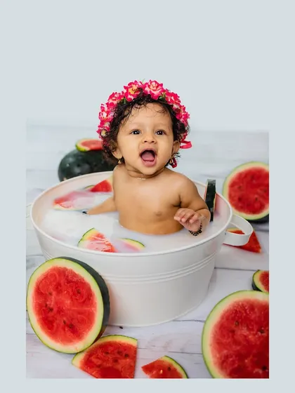 A vibrant and playful shot of a baby enjoying a milk bath filled with fresh watermelon slices. This highlights our creative and fun themed sessions for capturing your baby's personality.