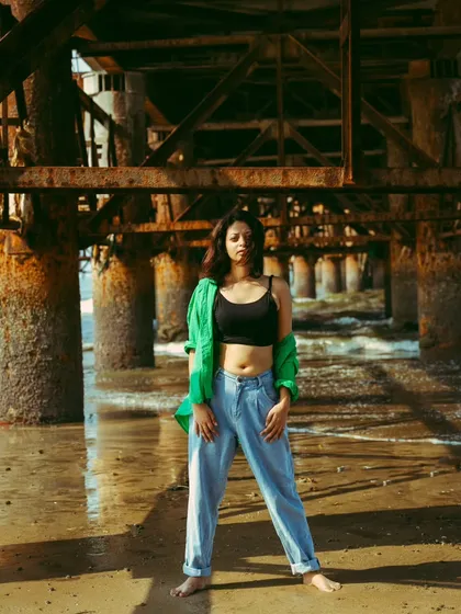 A full-length stance under the pier, showcasing the complete outfit and the cool, relaxed attitude of the shoot.