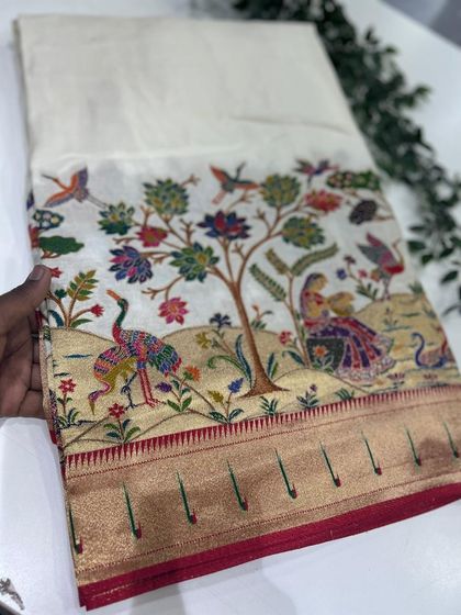 The same exquisite Dola Paithani design on a classic off-white base, allowing the colorful woven motifs to truly stand out.