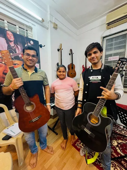 Two of our adult guitar students and a young peer pose with their instruments. This photo perfectly illustrates the all-ages community we have built at The Music Gurukul.