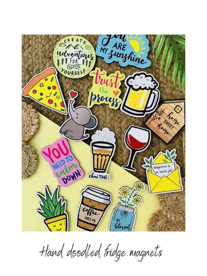 A collection of our little handmade creations, all priced under ₹500. This image shows our hand-doodled fridge magnets with various fun designs and quotes, perfect for adding a bit of joy to your kitchen.