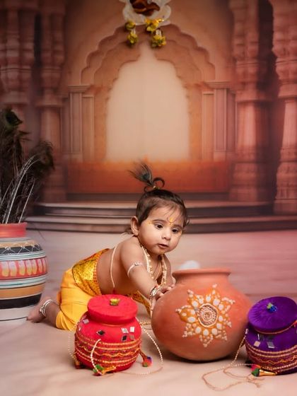 The curiosity of a baby exploring his surroundings. Dressed as Krishna, this little one crawls towards the colorful pots, creating a perfect candid shot during his first photoshoot.