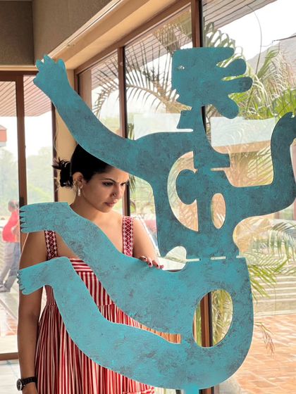 A moment of reflection (or existential dread) in the studio, holding a newly fabricated metal sculpture. It's a glimpse into the life of an artist, balancing creation with contemplation.