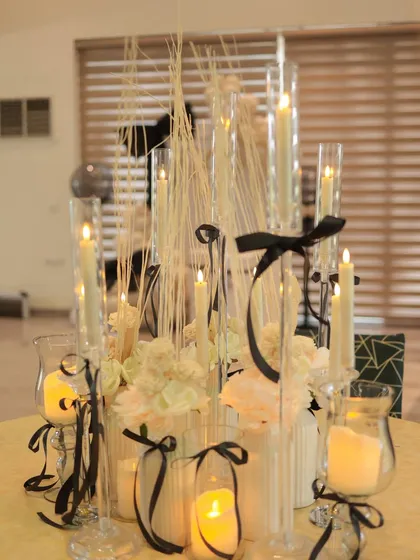 A beautiful and intricate centerpiece for a bow themed party. We used tall glass candle holders, white flowers, and delicate black ribbons to create a dramatic and romantic tablescape.