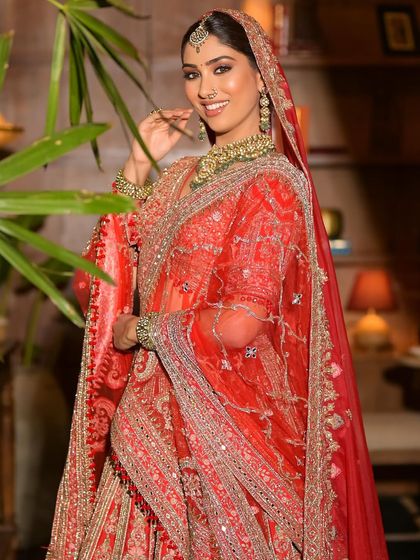 A full-length shot of a model in a stunning red lehenga, perfect for a bridal photoshoot or the wedding day itself.
