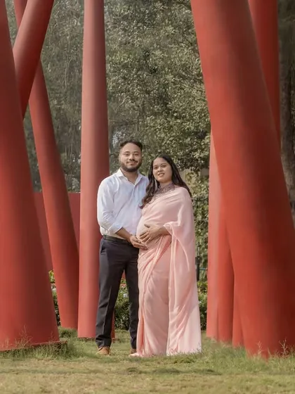 A unique outdoor shot using modern red pillars as a framing device for this couple's portrait in a pink saree.