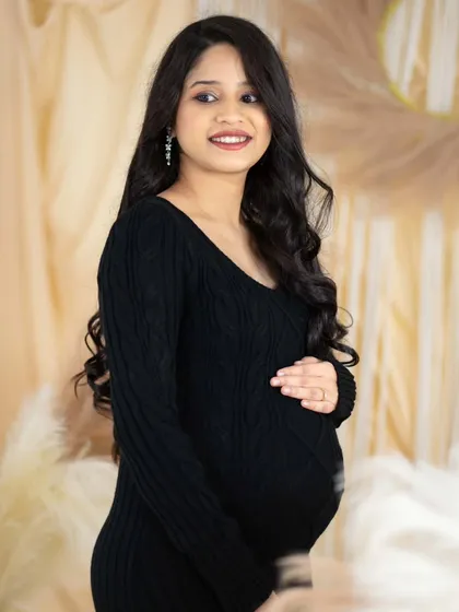 A simple and elegant portrait of a mom-to-be in a black knit dress. The neutral boho backdrop complements her classic look perfectly.