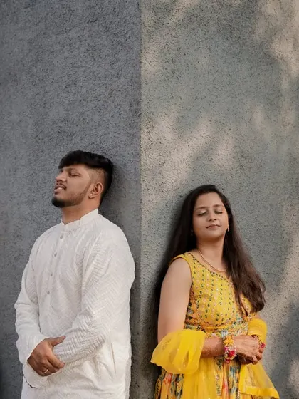 An artistic, posed shot of the couple against a modern, urban wall, showing a different, more contemporary style for Haldi photos.