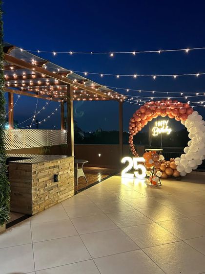 A wider angle of the rooftop 25th birthday, showcasing the spacious setup with string lights creating a magical atmosphere.