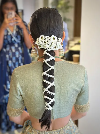 A beautiful bridal braid for a destination wedding in Udaipur, adorned with a string of pearls and a cluster of fresh daisies.
