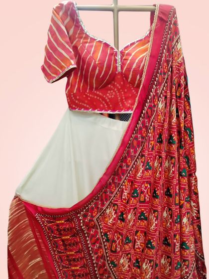 A close-up of the white and red lehenga, focusing on the intricate patterns of the traditional red dupatta.