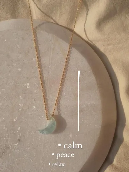 The aquamarine Luna pendant, a simple charm for calm, peace, and relaxation. Its energy is as soothing as its sea-blue color.