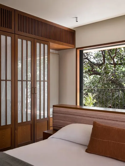 A full view of the master bedroom's custom island bed and headboard. The low height of the headboard ensures the view of the trees outside remains the main event.
