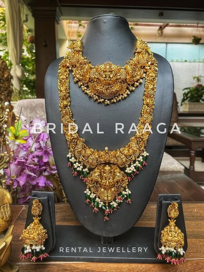 This grand bridal set features a choker and a long haram with intricate carvings, accented with green and red beads for a traditional look.