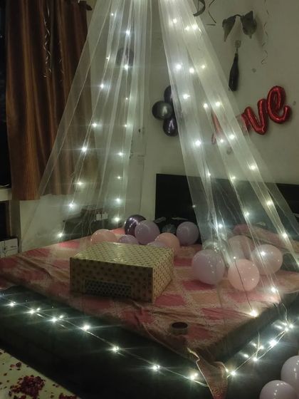 A simple and magical room surprise using a sheer canopy with fairy lights over the bed, surrounded by balloons.