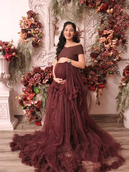 A beautiful standing portrait of the expectant mother cradling her belly. The full floral arch frames her perfectly, highlighting the joy and anticipation of this special time.