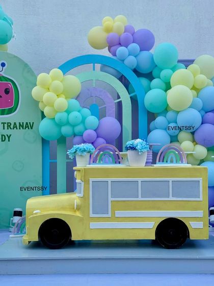 A close-up of the iconic yellow Cocomelon school bus prop, decorated with rainbow flower pots.
