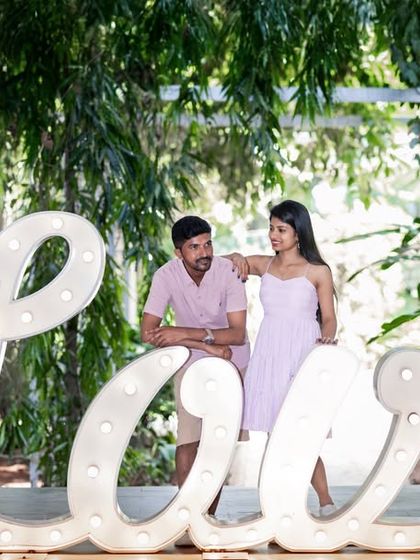 A fun and casual shot with the large, illuminated 'Love' sign, perfect for capturing a couple's playful side.