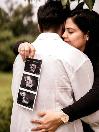 An intimate close-up of the mom-to-be hugging her partner from behind, holding the sonogram pictures against his back. It’s a creative and loving way to include the baby in their embrace.