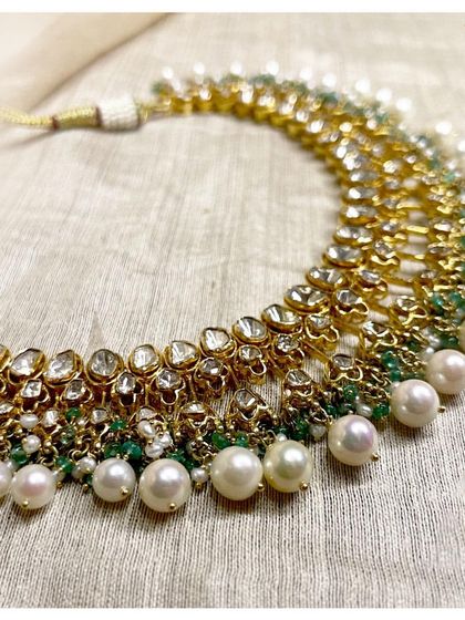 A classic polki and pearl choker. This exquisite piece is set with dazzling uncut diamonds and complemented by the delicate lustre of pearls and emeralds, perfect for any celebration.