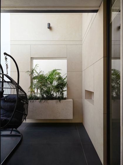 Even small spaces can provide a moment of escape. This private balcony in Villa Aish, with its minimalist planter and comfortable swing chair, serves as a quiet, contemplative nook that seamlessly extends from the interior.