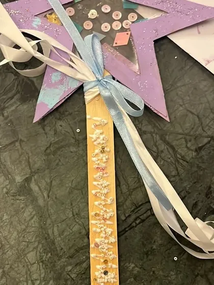 A close-up of a beautifully decorated wishing wand, complete with ribbons and sequins. A perfect craft for celebrating new beginnings.