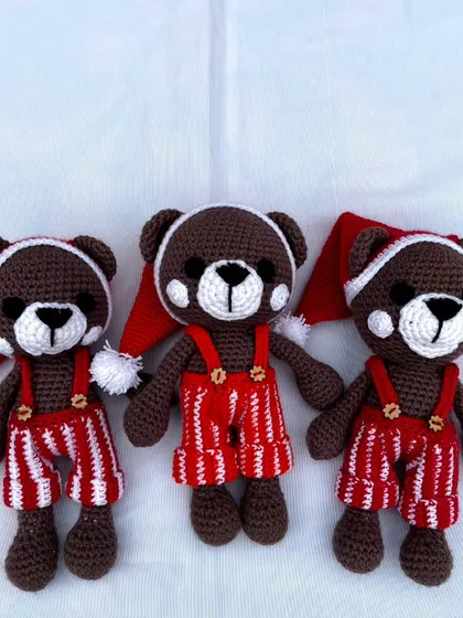 A trio of festive teddy bears dressed in Santa hats and striped overalls, ready for the Christmas season.