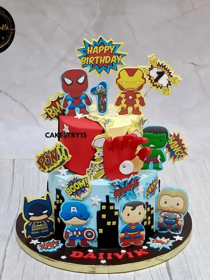 For the little superhero in your life, this two-tier Avengers-themed cake is packed with action. It features edible images of Spiderman, Iron Man, Hulk, and Captain America against a city skyline, complete with comic book sound effects like 'POW!' and 'BAM!'.