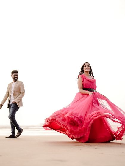 A fun and dynamic shot of the bride-to-be twirling in her pink ruffled gown on the beach. It perfectly captures a moment of joy.