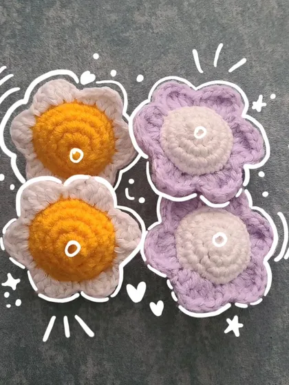 A cute collection of my crochet flower heads, showing off the daisy and pansy styles I create. This image features two white and yellow daisies and two purple and white pansies, perfect for turning into coasters, appliques, or parts of a larger floral project.