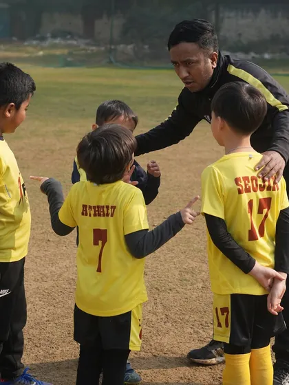 Teamwork starts with clear communication. A coach gathers his players to explain a drill, ensuring everyone understands their role and the importance of working together.