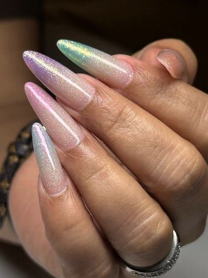 A magical, multi-toned glitter manicure on long, stiletto-shaped nails. The glitter appears to shift from pink to green to silver in the light.