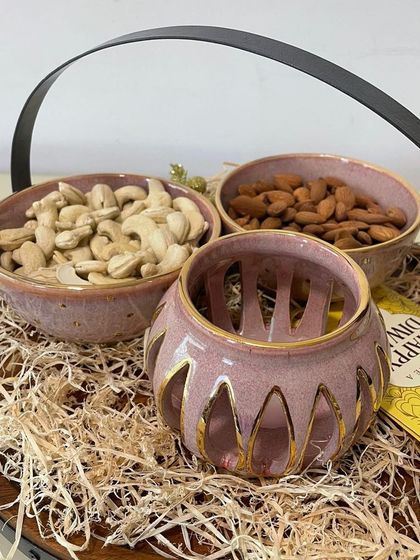 The Diwali hamper includes two small bowls for serving dry fruits and a beautiful perforated tealight holder that casts a warm, golden glow.