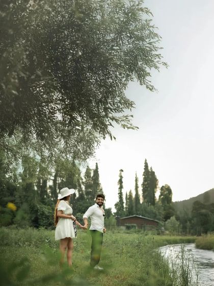 A candid moment of joy by a riverside. The couple shares a laugh, their happiness illuminated by the natural light, creating a fresh and lively portrait.