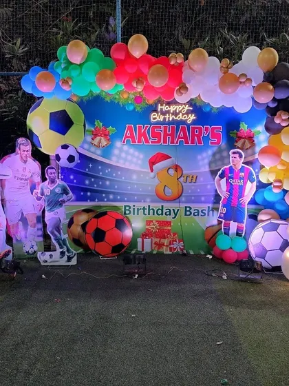 Akshar's 8th birthday football party setup on a turf, with a stadium backdrop and cutouts of famous football players.