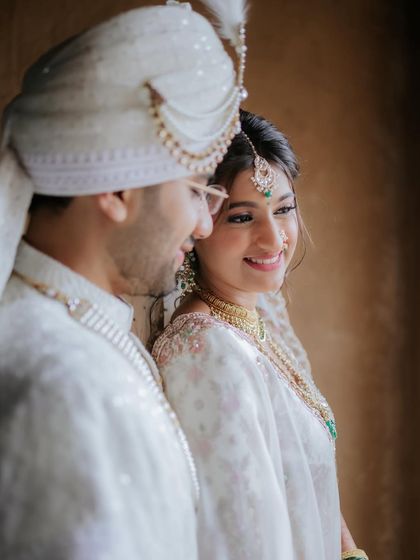 A sweet, candid moment between the bride and groom. Her natural, glowing makeup looks beautiful next to his classic white sherwani.