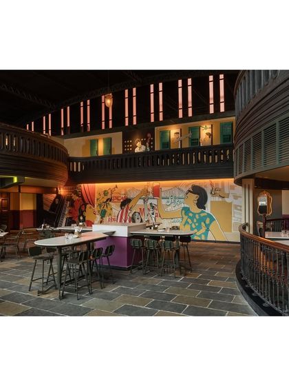 Another view of the mural and the multi-level seating, showing how the artwork is integrated into the architecture. The upper balcony features cutouts that offer glimpses of the activity below.