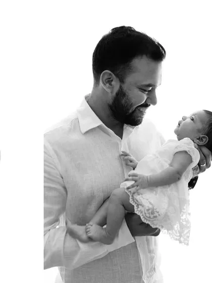 A father's gentle gaze at his newborn daughter. These are the quiet, powerful moments we aim to capture in every family session.