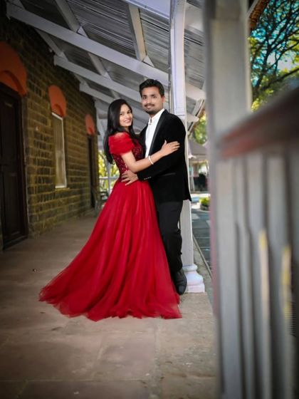 An elegant pose on a vintage-style porch. This couple's pre-wedding photo has a timeless feel, thanks to the classic red gown and black blazer.