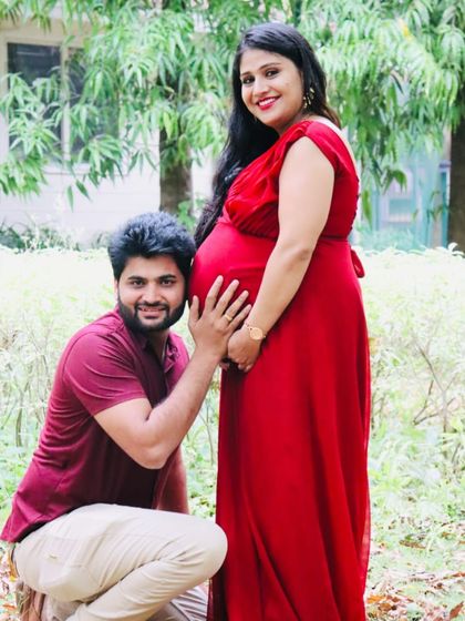 A heartwarming family moment as a partner listens to the baby bump. The simple yet elegant red maternity gown is perfect for capturing these precious, intimate memories.